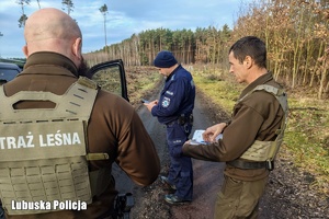 Policjant i strażnicy leśni kontrolują pojazd.
