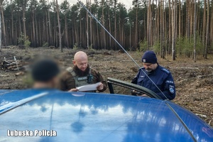 Policjant i Strażnik Leśny sprawdzają dokumenty.